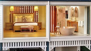 A bedroom with a bed, nightstands, and a bedside lamp. The bathroom features a bathtub, sink, and mirror. - Paddock View Ranch in the Sunny Coast Countryside (Belli Park)