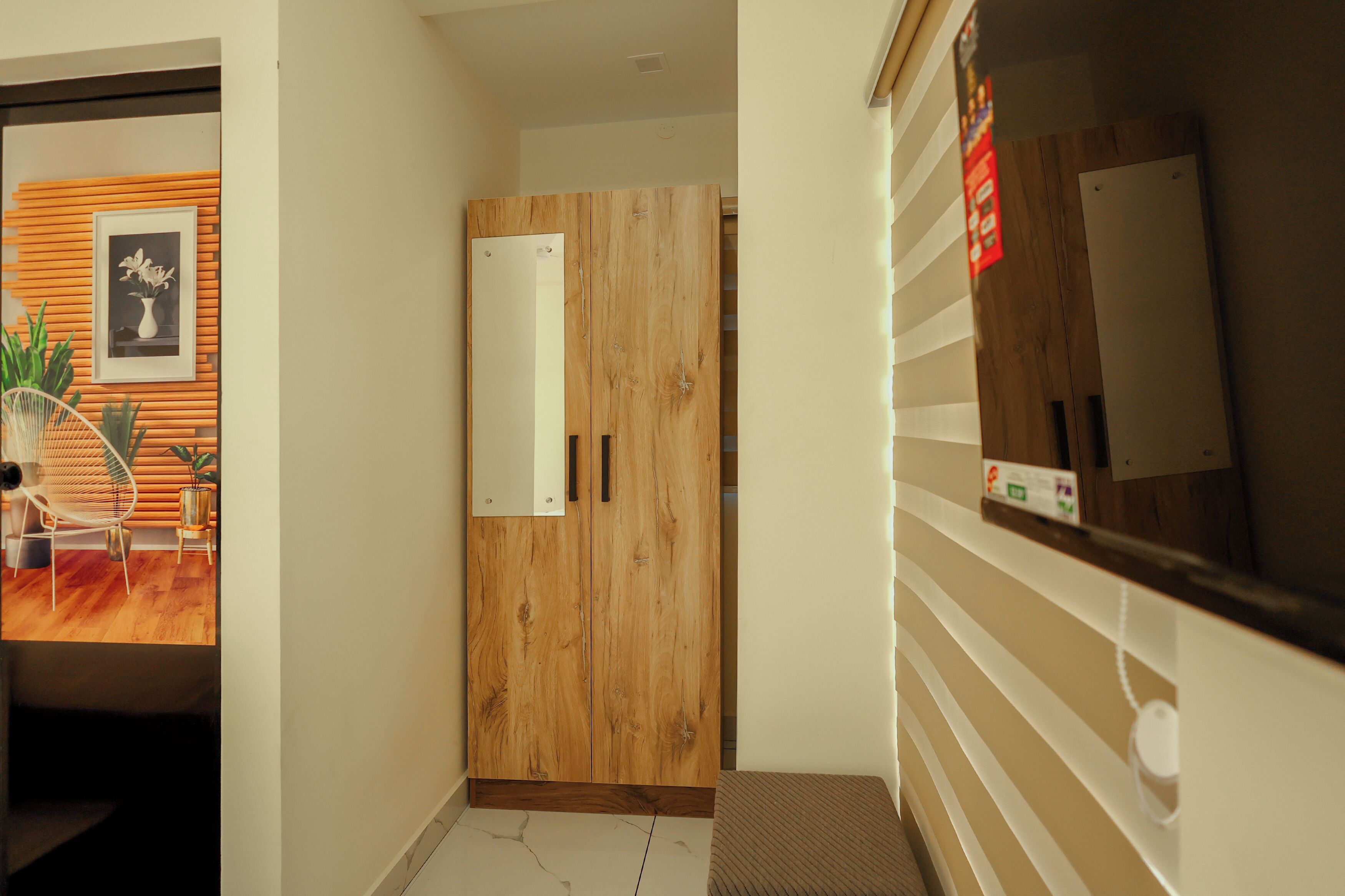 Un couloir avec une armoire en bois, un tableau encadré au mur et une plante.