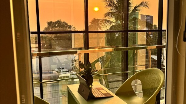 A balcony with a view of the sunset, a laptop, a plant, and two chairs. - MOONIC DAYS (Kanayannur)
