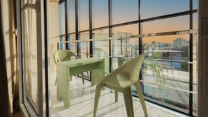 A modern room with a large window, a green desk, and a chair. - MOONIC DAYS (Kanayannur)