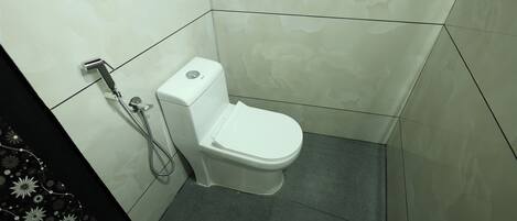 A small, modern bathroom with a white toilet and a shower unit.