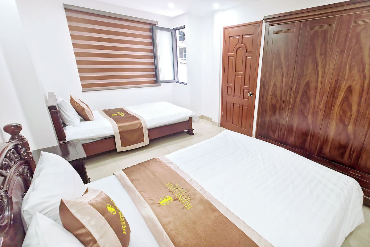 A hotel room with two beds, a wardrobe, a window with blinds, and a door.