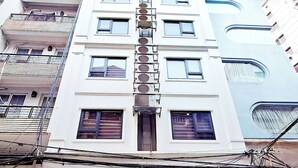 A multi-story hotel with a central staircase, a coffee shop at the ground level, and a visible sign for a restaurant. - Huong Linh Apartment (Hanoi)