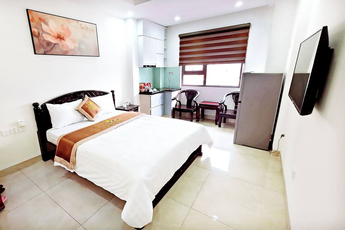 A hotel room with a bed, a desk, a chair, a TV, and a window.