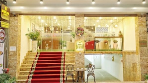 A hotel entrance with a red carpet, a staircase, and a reception area with a Christmas wreath. - Huong Linh Apartment (Hanoi)