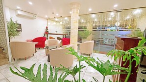 A hotel lobby with seating, a reception desk, and a view of the street. - Huong Linh Apartment (Hanoi)
