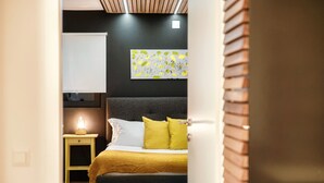 A bedroom with a bed, a bedside table with a lamp, a wall-mounted artwork, and a door leading to another room. - Between the hills bordering Italy (Modern Flat) (Vacallo)