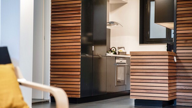 A modern kitchen with wooden paneling, a built-in oven, and a kettle on the counter. - Between the hills bordering Italy (Modern Flat) (Vacallo)