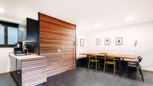 A modern kitchen with a built-in stove, a wooden partition, and a dining area with a table and chairs. - Between the hills bordering Italy (Modern Flat) (Vacallo)