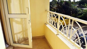A balcony with a yellow wall and a white railing.