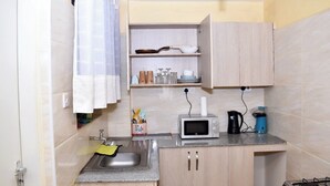 A compact kitchen with a sink, a microwave, a kettle, and a gas stove.