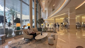 Eine geräumige Lobby mit Sitzgelegenheiten, großen Fenstern und einer modernen Kronleuchter.