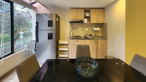 A compact kitchen with a refrigerator, stove, and wooden cabinets. - Cozy Loft Chpinero in Bogot (Bogotá)