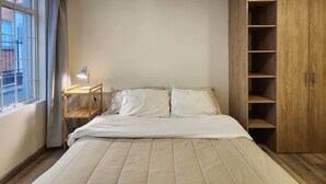 A bedroom with a bed, a nightstand, a lamp, and a wooden wardrobe. - Cozy Loft Chpinero in Bogot (Bogotá)