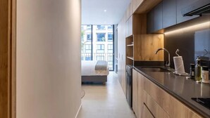 Una cocina moderna con armarios de madera, un lavamanos de acero inoxidable y un horno empotrado.