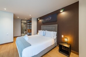 A modern hotel room with a large bed, a bedside table with a lamp, and a wall-mounted artwork. - Amazing Studio in Candelaria (Bogotá)