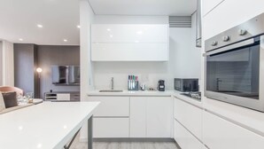 A modern kitchen with white cabinetry, a built-in oven, and a flat-screen TV. - Cozy 3 Br Apartment in Usaquen (Bogotá)