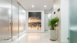 A modern hallway with a glass door, a large abstract painting, and a potted plant. - Cozy 3 Br Apartment in Usaquen (Bogotá)