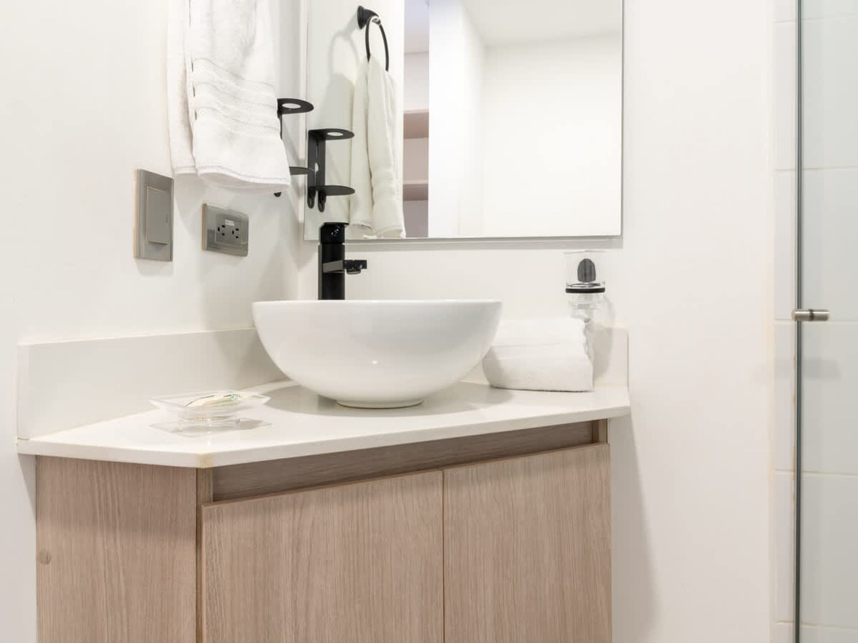 A modern bathroom with a white sink, a mirror, and a towel rack.