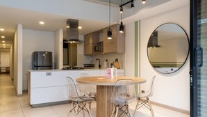 A modern kitchen with a central island, clear chairs, and a round table. - Cozy 3 BR w Balcony in Laureles Medell n (Medellín)