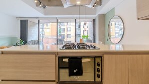 Een moderne keuken met een centraal eiland, een ingebouwde oven en grote ramen met uitzicht op de stad.