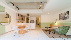Een moderne keuken met witte kasten, een ronde eettafel en hanglampen.