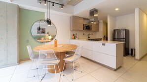 Een moderne keuken met een centraal eiland, witte kasten en een roestvrijstalen koelkast.