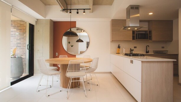 A modern kitchen with a central island, white chairs, and a round mirror on the wall. - Cozy 3 BR in Laureles in Medell n (Medellín)