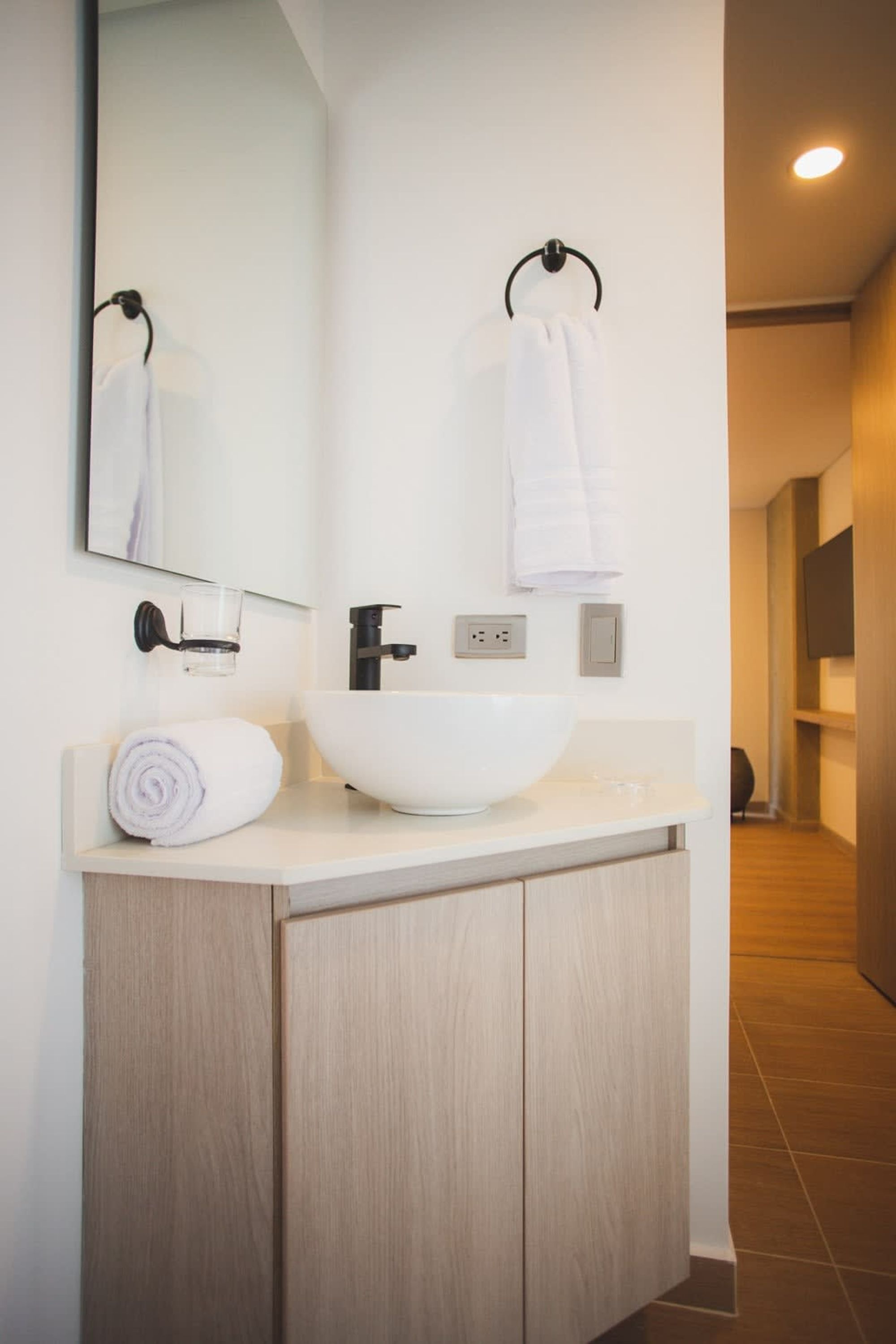 A modern bathroom with a white sink, a mirror, and a towel rack.