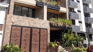 A multi-story building with balconies, brick facade, and a gated entrance with plants. - Cozy 3 BR in Laureles in Medell n (Medellín)