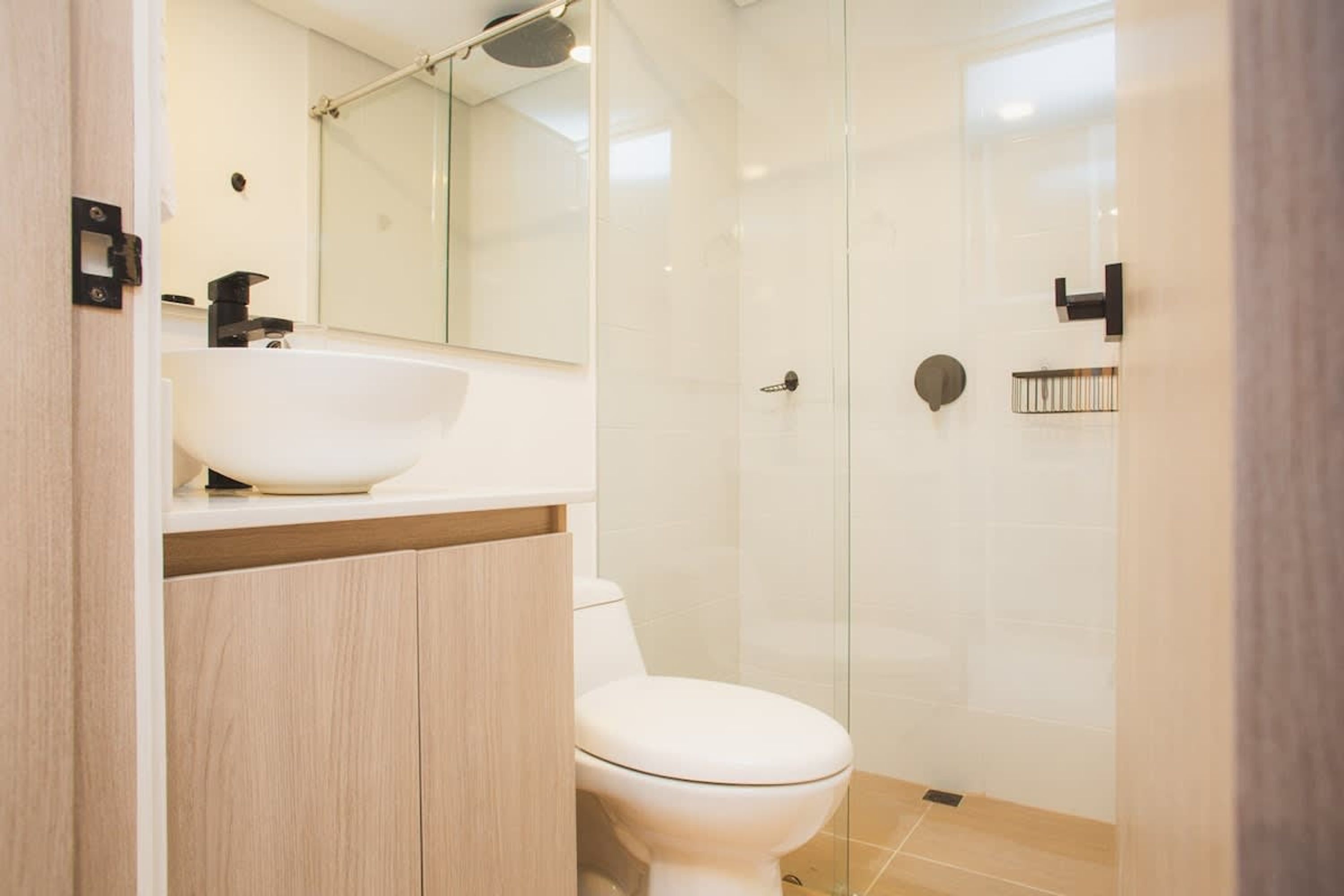 A modern bathroom with a white sink, mirror, and toilet.