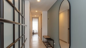 A hallway with a bench, a large mirror, and a door leading to another room. - Beautiful 3BR in Laureles Medell n (Medellín)