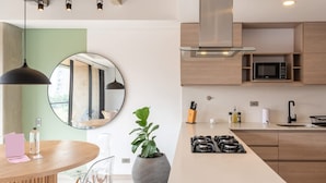 A modern kitchen with a central island, built-in microwave, and stainless steel range hood. - Beautiful 3BR in Laureles Medell n (Medellín)