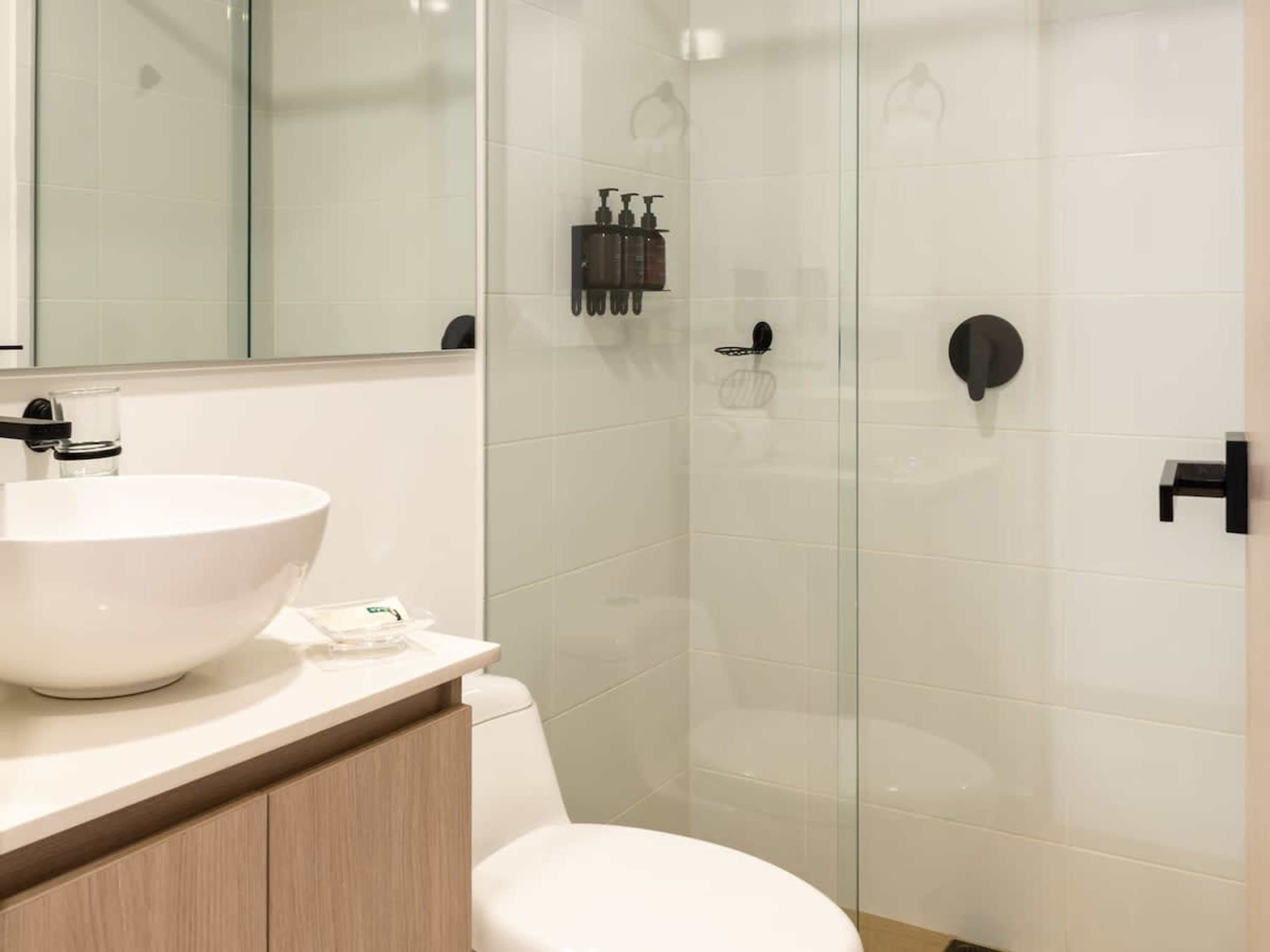 A modern bathroom with a white sink, a toilet, and a glass-enclosed shower area.