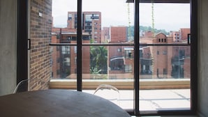 A room with a large window, a brick wall, and a wooden ceiling. - Perfect 3 BR in Laureles in Medell n (Medellín)