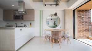 A modern kitchen with a central island, a dining area with a round table and chairs, and a large mirror on the wall. - Perfect 3 BR in Laureles in Medell n (Medellín)