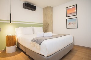 A neatly made bed with white bedding, a bedside lamp, and two framed pictures on the wall. - Perfect 3 BR in Laureles in Medell n (Medellín)