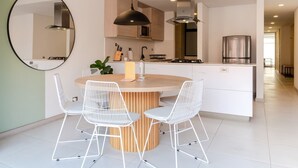 A modern kitchen with a central island, white chairs, and a large mirror. - Bright 3BR in Laureles Medell n (Medellín)