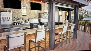 Un área de bar al aire libre con pared de ladrillo, taburetes de bar y vista a un cuerpo de agua.