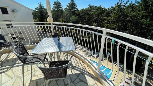 Ein Balkon mit Tisch und Stühlen, ein kleiner Pool und eine Geländer.