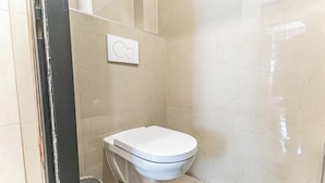 A bathroom with a toilet, a wall-mounted flush handle, and a trash bin. - 4BR Apt. for Groups 6-Min to Stadthalle (Vienna)
