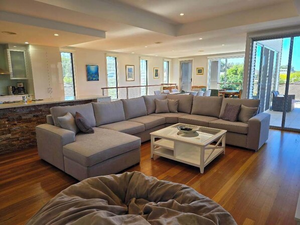 A modern living room with a sectional sofa, a coffee table, and a stone accent wall. - The Sandcastle: Steps to the Beach (Long Beach)