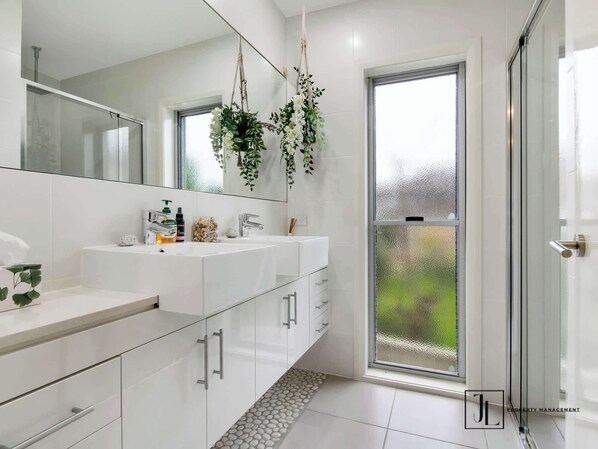 A modern bathroom with a large mirror, two sinks, and a shower area. - The Sandcastle: Steps to the Beach (Long Beach)