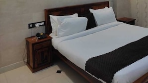 A modern hotel room with a large bed, bedside tables, an air conditioning unit, and a ceiling with blue lighting. - LAVIT HOTEL (Faridabad)