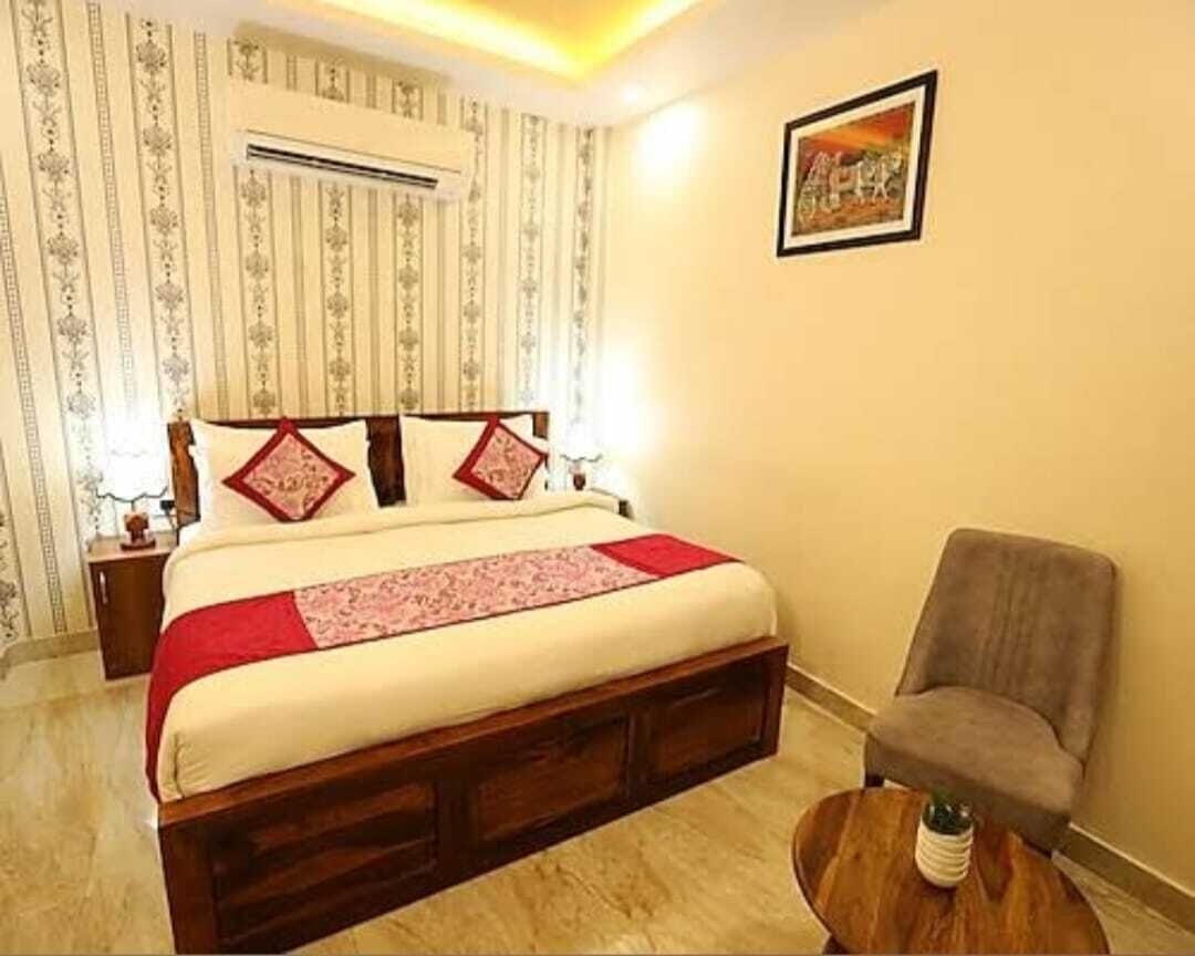 Quarto com cama, cadeira, mesa de cabeceira e ar-condicionado fixado na parede.