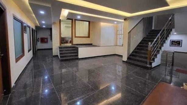 A spacious lobby with a polished floor, a central staircase, and a reception desk. - LAVIT HOTEL (Faridabad)