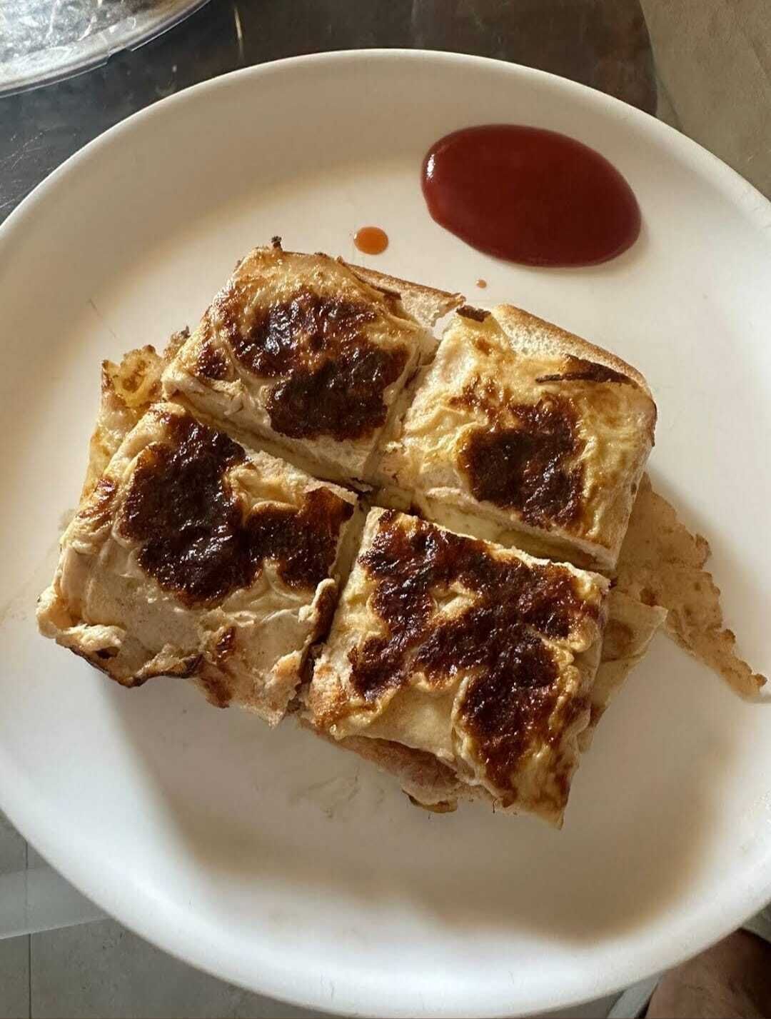 Un plat amb quatre entrepans de formatge a la planxa i una mica de ketchup.