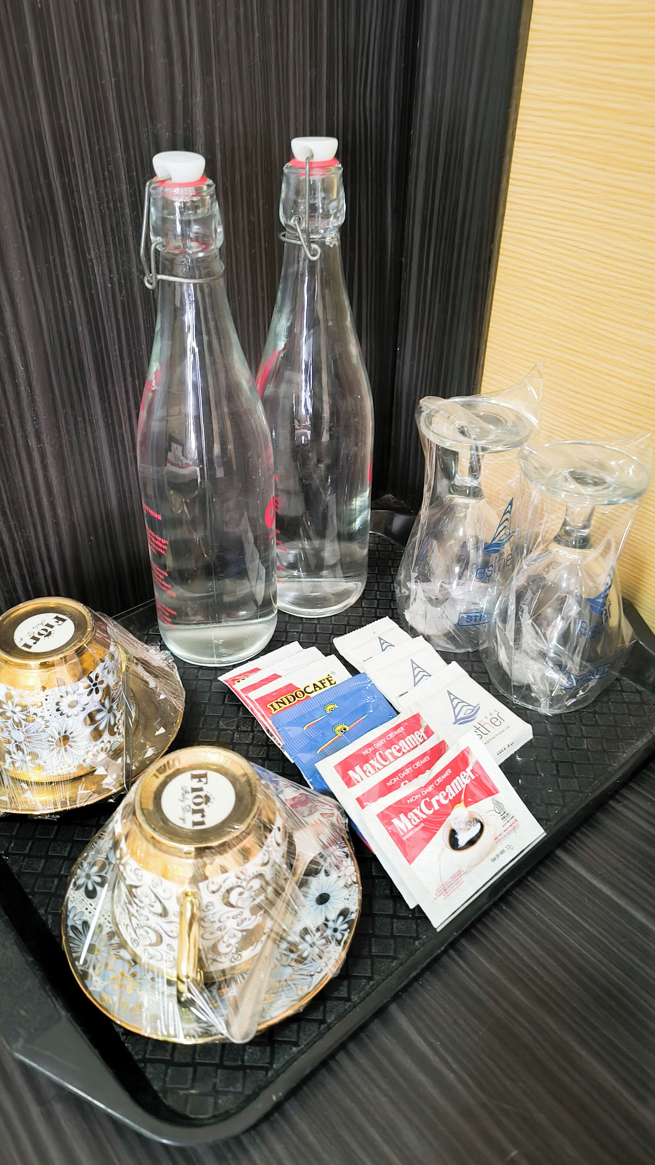 A tray with various glass bottles, a decorative plate, and two packets of MaxCreme.