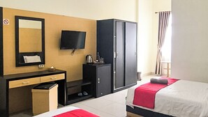 Hotellihuone, jossa on kaksi sänkyä, kirjoituspöytä peilillä, televisio ja vaatekaappi.