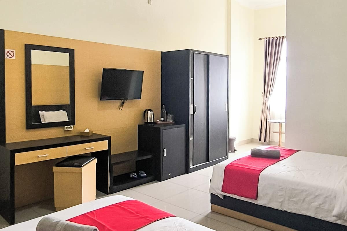 A hotel room with two beds, a desk with a mirror, a television, and a wardrobe.